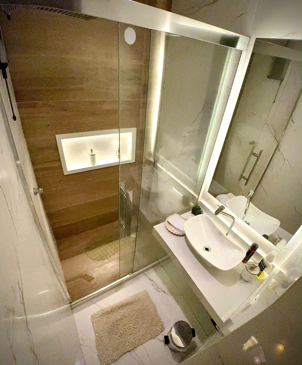 Banheiro com ducha, revestimento marmorizado e bancada iluminada na Zen Terapias